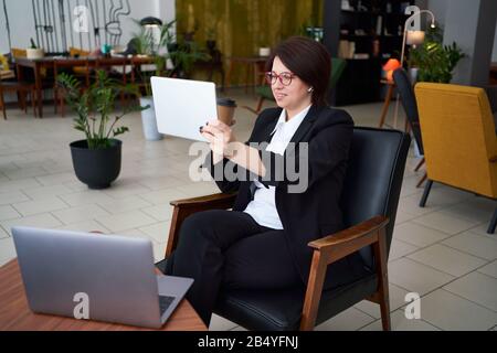 Jeune femme d'affaires ayant un appel vidéo avec une tablette pendant une pause de conflit Banque D'Images