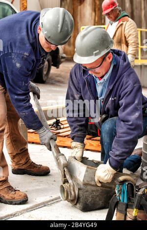 Deux électriciens masculins installant de nouveaux équipements dans une usine industrielle. Banque D'Images