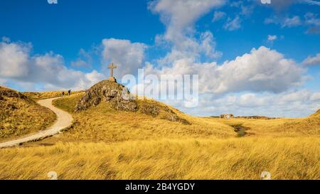 Vue sur le chemin côtier et les ruines de l'église St Dwynwen et les croix celtiques et modernes de l'île Llanddwyn, Anglesey Banque D'Images