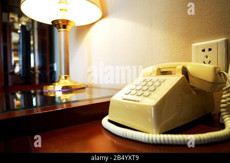 ancien téléphone sur une table en bois près du mur et de la rampe dans la chambre de l'hôtel Banque D'Images
