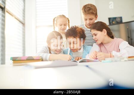 Groupe de bons amis aidant un garçon de douze ans avec des devoirs qu'il ne pouvait pas faire, photo horizontale Banque D'Images