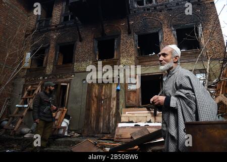 L'homme de Kashmiri et le personnel de police se tenant à l'extérieur de la maison blazée au lendemain.un couple et leur fille de trois ans ont été charmés à mort dans un blaze qui a éclaté dans la région de Khanyar de Srinagar, les responsables disent que l'incendie a éclaté d'une maison résidentielle dans la nuit. La police a entamé une enquête sur la question et une affaire a également été enregistrée. Banque D'Images