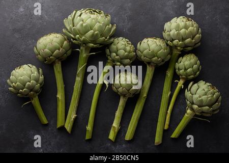 Artichauts verts frais sur fond noir Banque D'Images