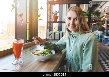 une femme en bonne santé qui déjeune au restaurant. manger de la salade de ceasar avec du jus de carotte frais Banque D'Images