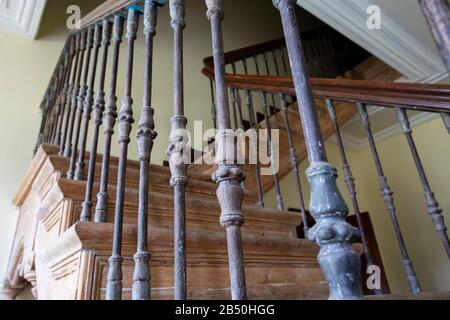 Ancien escalier avec balustres en fer et rampe en bois. Banque D'Images