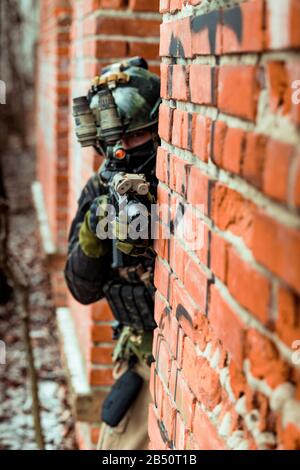 Gros plan militaire en uniforme de camouflage noir vise à partir du coin de la rue Banque D'Images