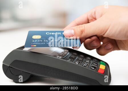 L'homme à l'aide de carte de crédit en magasin. Paiement sans espèces avec terminal de point de vente Banque D'Images