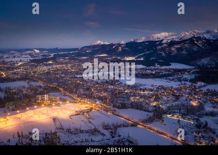 Ville illuminée à couper le souffle de Zakopane après le crépuscule en hiver, vue aérienne Banque D'Images