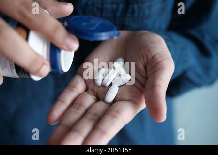 Verser les pilules de la bouteille blanche dans la main . Banque D'Images