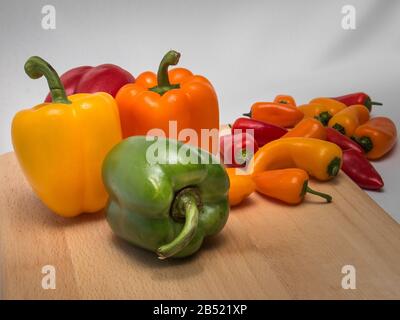 Intérieur encore vie d'un assortiment de poivrons colorés sur un tableau de découpe en bois Banque D'Images
