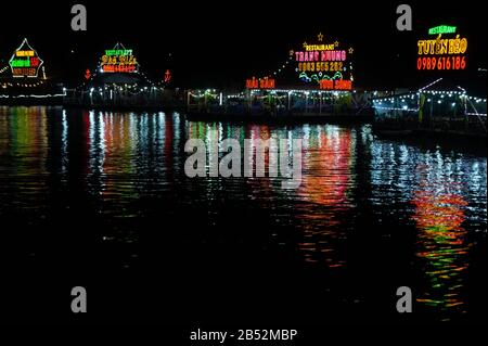 Cat Ba Island, Vietnam 17 Octobre 2019. Restaurants sur l'eau la nuit. Réflexion de couleur sur l'eau noire Banque D'Images