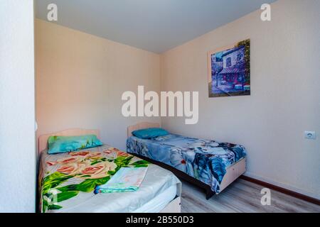 Une petite chambre dans la maison d'hôtes avec deux lits simples avec un couvre-lit vert et bleu. Banque D'Images