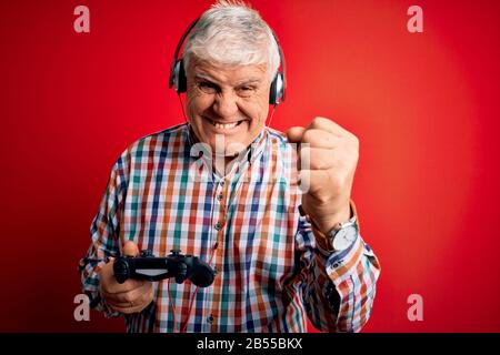 Un gamer hante senior jouant au jeu vidéo à l'aide d'un joystick et d'un casque énervé et frustré de crier avec colère, fou et hurlant avec la ra Banque D'Images