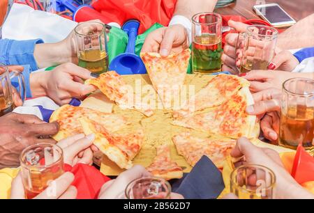 Les mains multiethniques du soutien d'ami de football partageant la pizza margherita - jeune fan de sport toaster la bière après match de jeu - concept d'amitié avec ainsi Banque D'Images