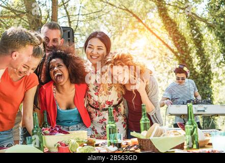 Groupe de jeunes ayant un festival de musique de fête de barbecue dans la nature - Des amis Heureux riant et buvant des bières dans un événement escusif avec dj set mélanger Banque D'Images
