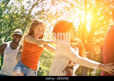 Des amis multiraciaux dansant dans le jardin pendant l'été - Des jeunes Gens Gaies s'amuser en plein air - concept d'amitié multiethnique - Soft foc Banque D'Images