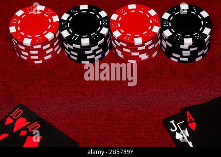 Gros plan sur les mains Black Jack avec des cartes et des jetons noirs et rouges avec les mains sur un plan de table en feutre rouge. Espace de copie au centre de l'image Banque D'Images