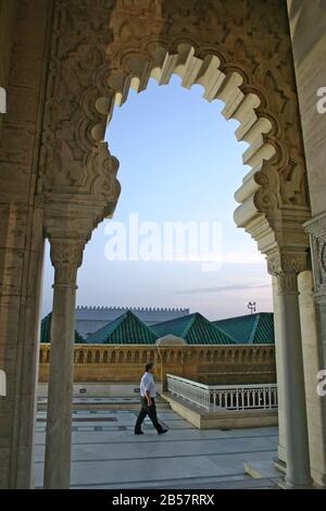 Un homme passe devant une arche de style islamique du mausolée de Mohammed V sur l'esplanade Yacoub al-Mansour au crépuscule à Rabaat. Banque D'Images