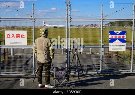 Homme non identifié prenant une photo d'avion à travers la clôture à l'aéroport de Fukuoka Banque D'Images