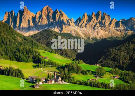 Vue majestueuse depuis la colline avec des champs verdoyants d'été et des montagnes hautes. Un endroit superbe avec une église alpine traditionnelle et des fermes de montagne à Santa Mad Banque D'Images