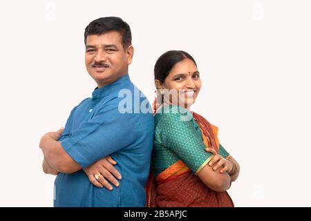 Les couples indiens heureux dans la robe traditionnelle avec les bras croisés se tenant debout à l'arrière sur fond isolé - concept de couple heureux et joyeux Banque D'Images