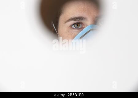 Une femme porte un masque facial pour la protection contre le virus Corona et s'est gardée sur son papier toilette en cas de quarantaine. Banque D'Images