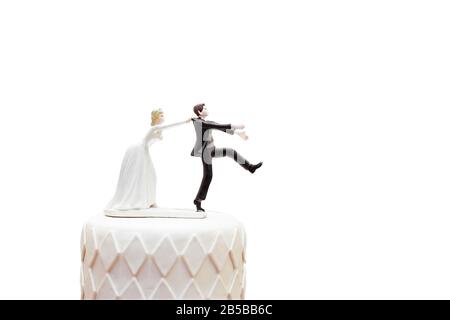 la poupée et la statue de groom s'en vont, mais la mariée peut le prendre enfin. la poupée drôle d'histoire de mariage sur le dessus du gâteau avec un objet isolé sur blanc b Banque D'Images