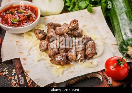 Brochettes de coeurs de poulet sur pain pita. Les aliments continuent de vivre avec de la viande, des sauces, des légumes, des herbes et des épices. Banque D'Images