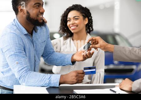 Les Conjoints Afro Paient Avec Une Voiture D'Achat De Carte Au Bureau De La Concession Banque D'Images