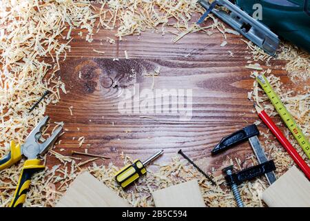 Scie sauteuse électrique avec de nombreuses briques en bois pleines de sciure. Sur une table en bois rayée, concept d'outils de travail. Banque D'Images