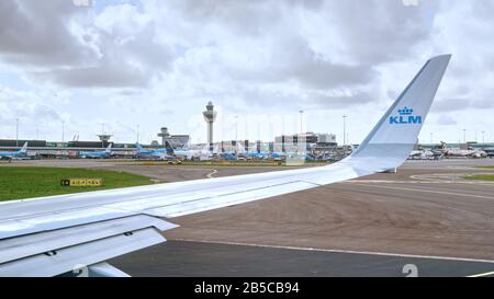 L'avion KLM Royal Dutch Airlines part à l'aéroport international d'Amsterdam Schiphol, aux Pays-Bas. Tablier avec avions et tour de contrôle de la circulation aérienne. Banque D'Images