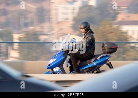 Belgrade, Serbie - 25 octobre 2019 : Un homme qui monte un scooter bleu dans le trafic sur le pont de la rue de la ville, panoramique tourné Banque D'Images