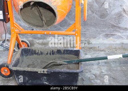 le travailleur de la construction pelle le sable dans le mélangeur de béton. processus de création de ciment sur le site de construction Banque D'Images