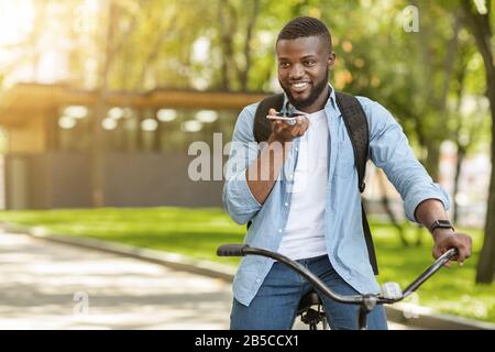 Afro Guy On Bicycle Donnant Des Commandes Vocales Au Smartphone, Ouverture Du Navigateur Banque D'Images