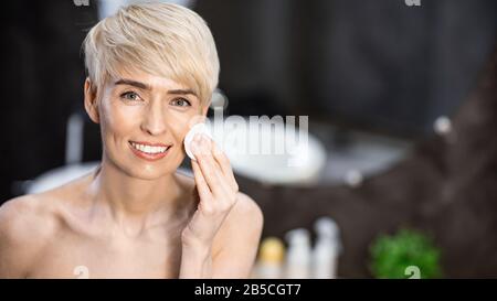 Femme Utilisant Un Tapis De Coton Hydratant Peau Debout Dans La Salle De Bains, Panorama Banque D'Images