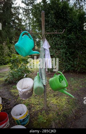 Sur un cimetière se tient un stand avec différents arrosoirs Banque D'Images