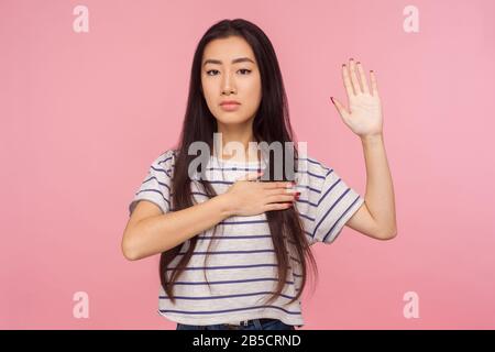 Je vous donne la promesse! Portrait d'une fille responsable et honnête avec des cheveux brunette gardant la main sur la poitrine et levant la paume pour prêter serment, pedging allégeance. Banque D'Images