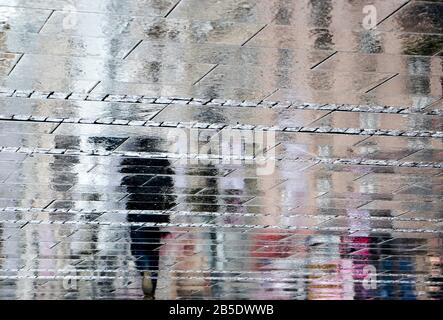 Résumé flou arrière-plan de réflexion ombre silhouette dans une flaque, des gens marchant seul rue de ville dans la pluie Banque D'Images