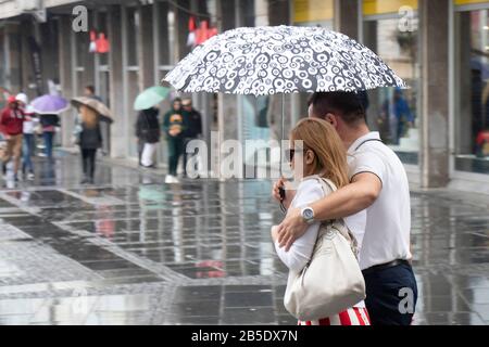 Belgrade, Serbie - 24 septembre 2019 : Couple marchant ensemble sous parapluie dans la rue de la ville pluvieuse Banque D'Images