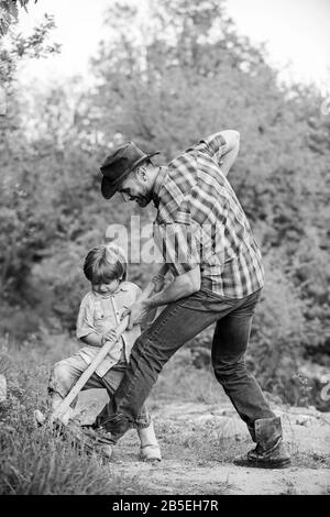 Trouvez des trésors. Petit garçon et père avec pelle à la recherche de trésors. Bonne enfance. Chasse aventure pour les trésors. Peu d'aide travaillant dans le jardin. Enfant mignon dans la nature s'amuser avec la pelle. Banque D'Images