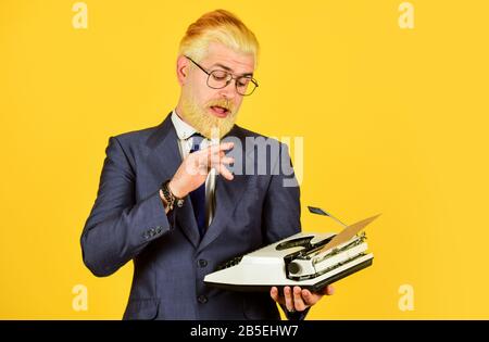 Connaisseur des valeurs vintage. Machine à écrire vintage. Les hommes d'affaires utilisent la technologie rétro. Homme mûr teint les cheveux de barbe fond jaune. Les vieux habitudes de l'auteur de bâton. Magasin de marchandises d'occasion. Objets anciens du vendeur. Banque D'Images