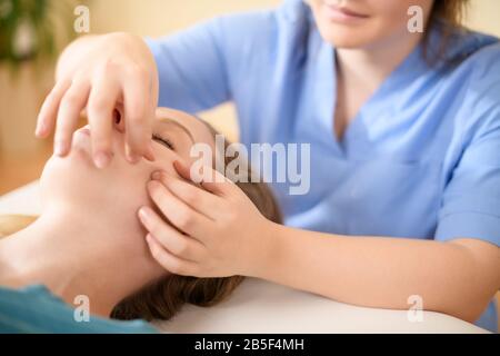 Belle jeune femme caucasienne ayant un massage du visage dans le salon de spa. Femme détendue avec massage du visage au spa. Banque D'Images