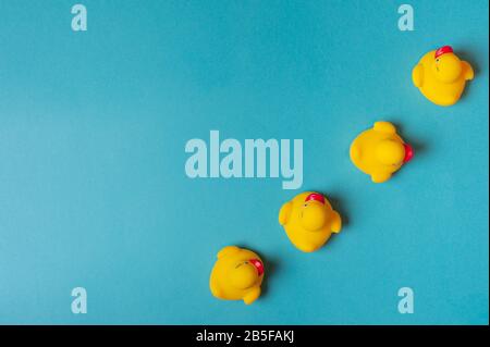 Quatre canards jaunes sur fond bleu. Concept de bain. Espace de copie, plat. Banque D'Images