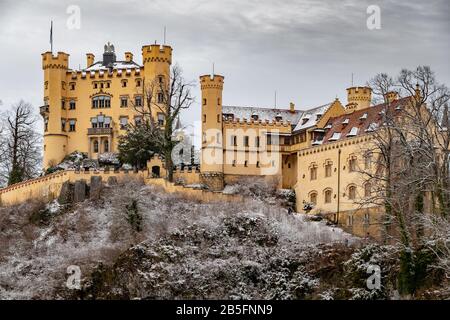 Le château royal de Hohenschwangau à Schwangau, Bavière, Allemagne (Deutschland). Le célèbre panneau de la place bavaroise le jour de l'hiver, ciel nuageux, Revival gothique Banque D'Images