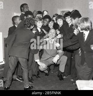 1972, historique, 'prenez-le sur le menton' .... la légende britannique de boxe Henry Cooper s'amuser avec un groupe de lycéens du sud de Londres lors d'une visite dans une école secondaire de la ville intérieure. Banque D'Images