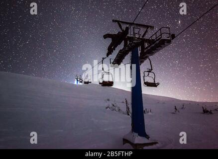 Les téléphériques accrochent sur les câbles dans une station de ski de nuit silencieuse contre un ciel étoilé magnifique lors d'une nuit d'hiver claire. Concept de vacances d'hiver et d'europe. Co Banque D'Images