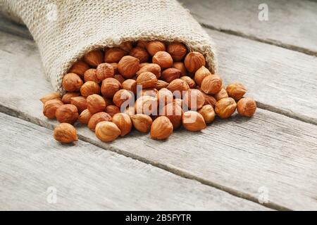 Noisettes ciselées dans un sac de burlap sur une table en bois gris. Récolte Fraîche Bio. Sans shell saine nourriture végétarienne super. Banque D'Images