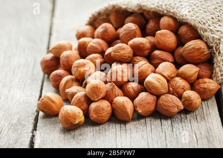 Noisettes ciselées dans un sac de burlap sur une table en bois gris. Récolte Fraîche Bio. Sans shell saine nourriture végétarienne super. Banque D'Images