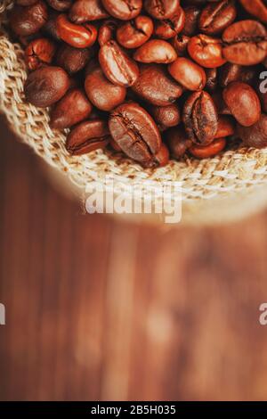 Grains de café se rapprochez dans un sac de burlap sur fond en bois. Contraste doux. Grains de café torréfiés aromatiques. La vue du haut. Macro Banque D'Images
