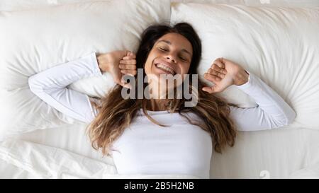 Bonne fille qui s'étire dans le lit se réveillant le matin Banque D'Images